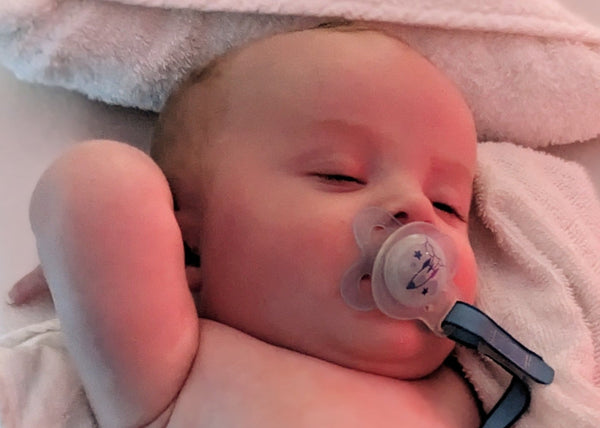 Newborn baby sleeping with a dummy, wrapped in soft towels